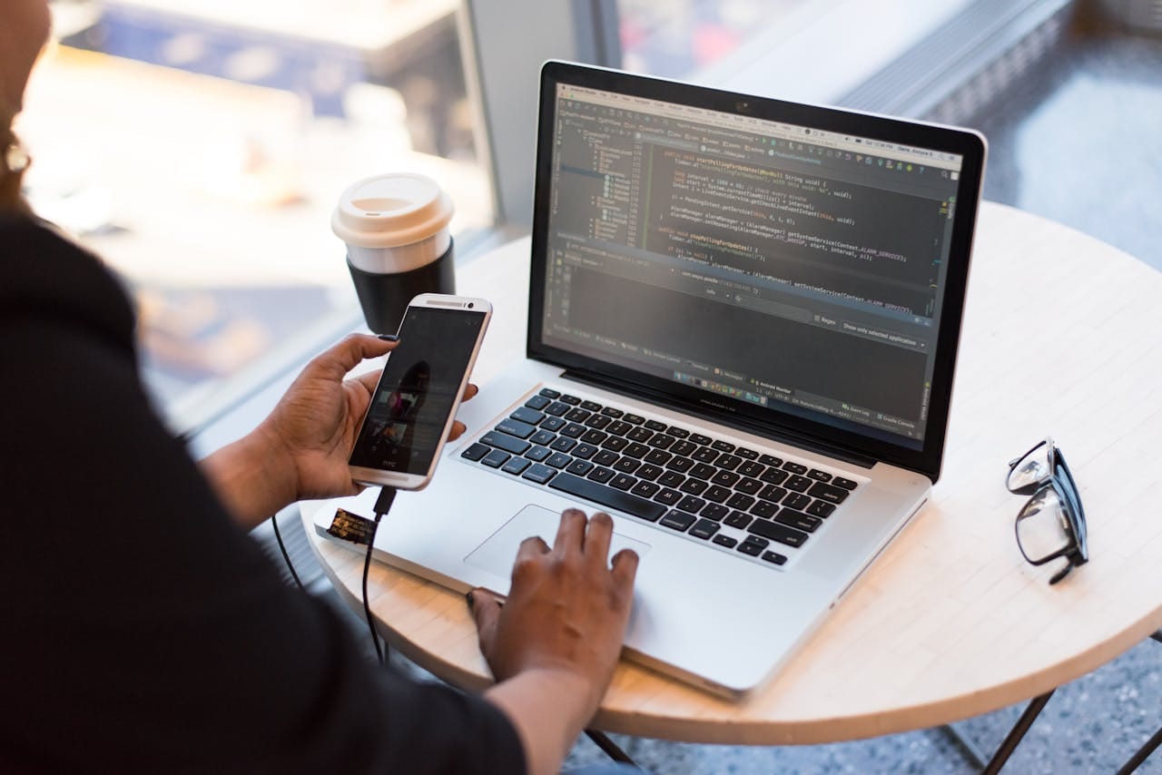 person holding smartphone while using laptop 1181244 Serviços