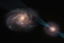 This artist’s impression shows a galactic merger in which the galaxy on the right hosts a quasar at its core; this quasar is powered by a supermassive black hole swallowing up material around it and emitting a powerful cone of radiation, piercing the other galaxy like a lance; as this radiation interacts with the galaxy on the left, it disrupts the clouds of gas and dust within, leaving behind only the smallest and densest regions; these regions are likely rendered incapable of star formation after the process. Image credit: ESO / M. Kornmesser.