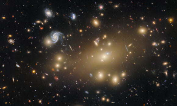 This Hubble image shows Abell 209, a galaxy cluster located about 2.8 billion light-years away in the constellation of Cetus. The color image includes both optical and infrared observations from Hubble’s Advanced Camera for Surveys (ACS) and Wide Field Camera 3 (WFC3). Twelve filters were used to sample various wavelengths. The color results from assigning different hues to each monochromatic image associated with an individual filter. Image credit: NASA / ESA / Hubble / M. Postman / P. Kelly.