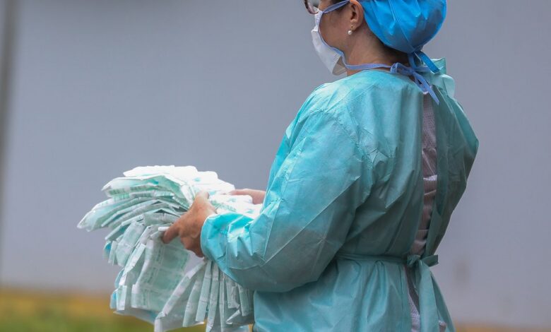 Cientista em laboratório avalia dados de vírus, com tela e microscópio, em foco concentrado.
